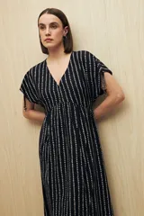Vestido largo negro con estampado de líneas verticales blancas, escote en V, mangas cortas con lazo ajustable y corte fluido.