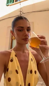 Vestido corto amarillo con lunares marrones, escote drapeado y tirantes finos.