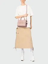 Bolso tote pequeño de cuero texturizado color gris con doble asa corta superior y correa larga extraíble y ajustable para llevar al hombro. Estampado frontal con el texto "The Tote Bag" y el nombre de la marca.