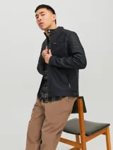 Campera negra de cuero sintético con cuello mao, cierre frontal con cremallera, bolsillos laterales y en el pecho con cremallera, mangas largas con detalle de costuras en los hombros.
