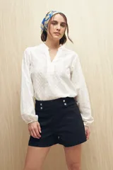 Short de jean negro de tiro alto con detalle de doble botón metálico en la cintura, bolsillos delanteros y traseros.
