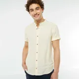 Camisa de lino color amarillo claro, de corte recto, con cuello mao, manga corta con dobladillo y cierre frontal con botones.