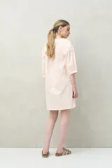 Vestido corto blanco de algodón con bordado floral en relieve, escote redondo con abotonadura frontal y mangas amplias.