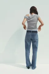 Camiseta blanca con musculosa gris superpuesta con escote asimétrico.