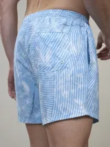 Short de baño verde con estampado de margaritas blancas y cordón ajustable naranja.