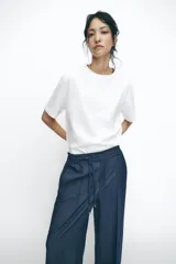 Pantalón de tiro alto azul denim, con cintura elástica ajustable con cordón, bolsillos laterales y traseros, y pernera ancha.