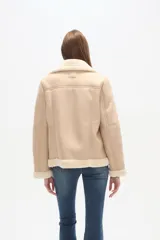 Campera tipo aviador de poliéster en color natural con forro de piel sintética a contraste. Presenta cuello de solapa, cierre frontal asimétrico con cremallera, bolsillos laterales con cierre y detalle de cremalleras en los puños.