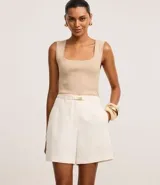 Short de vestir color crudo, de corte recto, con cintura alta, trabillas en la cintura, cinturón elástico con hebilla dorada y bolsillos falsos en la parte trasera.