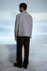 Sobrecamisa gris de tejido suave con cuello inglés, tapeta lisa, corte estándar, bolsillos superiores abiertos, abertura con botón en los puños, canesú en la espalda y bajo recto.