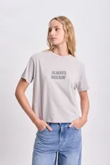 Remera gris claro de corte recto con cuello redondo y mangas cortas. Estampa frontal con la frase "Always Rockin'" en strass.