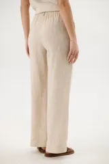 Pantalón de lino azul de corte palazzo con botón decorativo en la cintura.