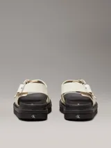 Sandalias de piel lisa color blanco con suela de goma negra, tiras anchas con hebillas metálicas ajustables y plantilla moldeada.