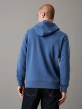 Buzo con capucha Calvin Klein color azul, de felpa de algodón y poliéster. Tiene corte regular, puños y bajo de canalé, capucha con cordón y logo bordado en el pecho.