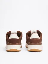 Zapatillas Tommy Jeans de corte bajo, color marrón, confeccionadas en gamuza con interior de poliéster y suela de goma. Presentan cordones, entresuela texturizada, etiqueta de la marca en el lateral y parche en la lengüeta.
