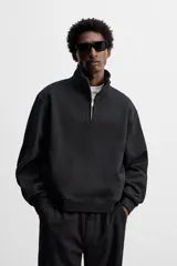 Sudadera negra de algodón con cuello alto y cierre de cremallera frontal. Corte relaxed fit, manga larga y terminaciones en rib.