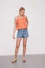 Musculosa color salmón con breteles finos y detalle de puntilla en el escote.