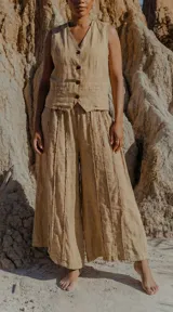 Conjunto de dos piezas color beige, compuesto por un chaleco sin mangas con botones frontales y un pantalón de tiro medio con pierna amplia y detalles de costura vertical.