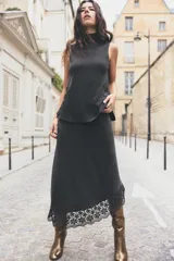 Top de punto canalé color gris oscuro, de cuello alto y sin mangas. Presenta apliques de encaje floral en los laterales del ruedo.