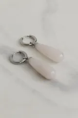 Par de aros colgantes con argolla de acero quirúrgico hipoalergénico y dije en forma de gota de piedra natural color rosa pálido.