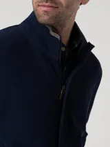 Buzo de hombre color azul marino, tejido de punto, con cuello alto y cierre frontal. Presenta un forro interior de cuello en gris claro.