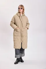Campera color beige con capucha, cierre frontal con cremallera y diseño acolchado con costuras en forma de rombos.