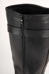 Bota de caña alta en símil cuero negro, con plataforma tipo tractor y hebilla decorativa.