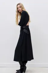 Vestido midi negro con escote redondo, espalda descubierta, mangas largas y frunces en cintura y cuello.