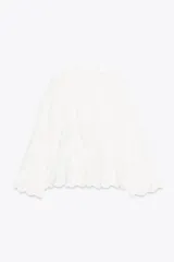 Blusa blanca de algodón con cuello solapa, escote pico y manga larga acampanada. Detalle de frunces y bordados a tono.