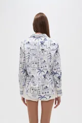 Camisa de manga larga con estampado de motivos playeros en tonos marrones sobre fondo beige, cuello camisero y cierre frontal con botones.