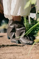 Bota texana marrón de caña media, con diseño superpuesto y tachas doradas.