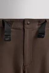Pantalón de hombre color beige/caqui, de corte regular fit, confeccionado en tejido técnico compacto con elasticidad. Presenta cintura ajustable con cinturón a contraste, bolsillos frontales, bolsillo trasero con cierre de cremallera oculta y bolsillo cargo con cierre de cremallera oculta en la pernera.