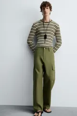 Pantalón cargo verde oliva de corte relaxed fit, confeccionado en tejido de algodón compacto con estructura twill. Cuenta con bolsillos frontales, traseros de vivo y bolsillos plastrón con solapa en las perneras.