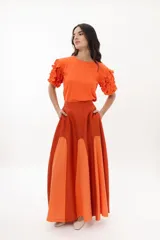 Falda larga de tencel color ladrillo, con paneles frontales color naranja, bolsillos laterales y cierre al costado.