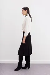 Falda midi negra de tejido de punto con cintura elastizada y diseño plisado.