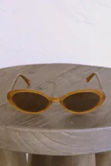 Lentes de sol color caramelo con forma ovalada y patillas con el logo de la marca Urban Haus.