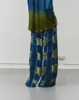Pantalón largo de pierna ancha color marrón con estampado degradado en tonos rosados y rojizos. Tiene cintura elástica, bolsillos laterales y costuras delanteras y traseras.