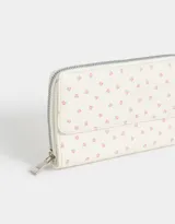 Billetera de cuerina estampada con cierre circundante y puller de material principal. Solapa con broche con botón para cerrado.