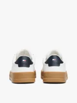 Zapatillas Tommy Hilfiger blancas de cuero, con suela marrón y detalle azul en el talón.