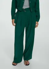 Pantalón verde esmeralda de corte ancho con pinzas, trabillas y cinturón decorativo con hebilla metálica.