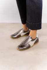 Zapatillas deportivas plateadas con detalles en blanco y suela color caramelo.