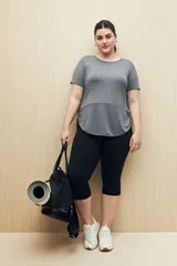 Remera deportiva gris de manga corta con calce relajado y corte horizontal en la parte inferior que genera un sutil efecto evasé.
