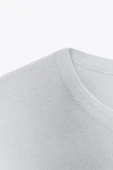 Top celeste de punto liso, corte amplio, cuello redondo, manga corta y aberturas laterales en el bajo.