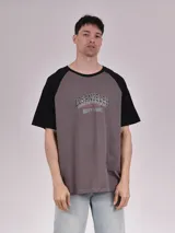 Remera gris con mangas cortas negras y estampado con texto 'Los Angeles Varsity League'.