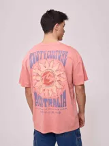 Remera de algodón con efecto lavado, color rosado, de calce oversize. Presenta un estampado grande en la espalda con un sol estilizado, el logo de Rusty y el texto "RUSTY CULTURE AUSTRALIA".