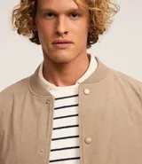 Campera bomber marrón de terciopelo pana con cuello redondo, cierre con botones a presión, bolsillos laterales, puños y cintura elastizados.