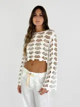 Top corto de crochet color blanco, con mangas largas acampanadas y diseño calado.
