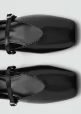Zapato tipo ballerina color negro charol, con punta redonda, cierre con hebilla y detalle de hebilla con strass.