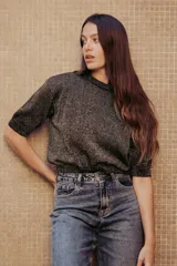 Sweater color dorado de tejido de punto suave con hilos metalizados, corte recto y mangas cortas con puño ajustado.