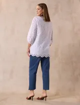 Blusa blanca de algodón con bordado broderie, cuello a la base con escote en V y mangas tres cuartos amplias con puño elastizado.