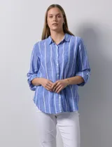 Camisa celeste con rayas verticales blancas, de lino, con cuello con solapa, abertura central con botones, bolsillo aplicado en el pecho y mangas 3/4 regulables con presilla y botón.